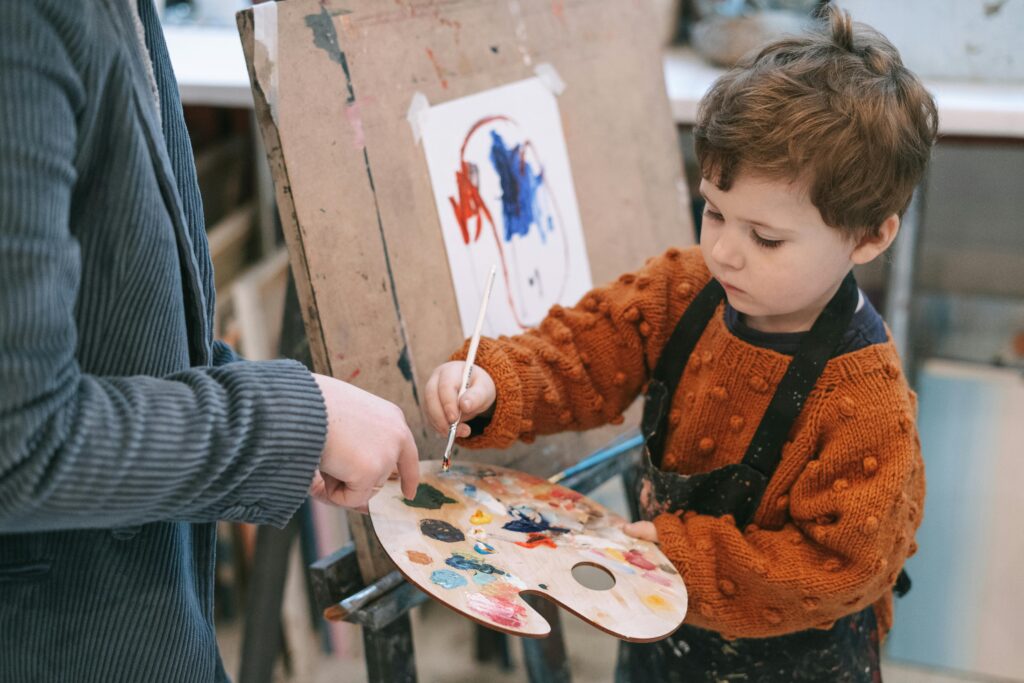 pexels-photo-6816531-6816531 Young boy learning to paint with teacher's guidance during art class.